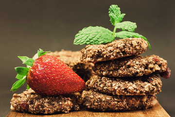 Brown oatmeal cookies with red strawberry on a wooden chopping board
