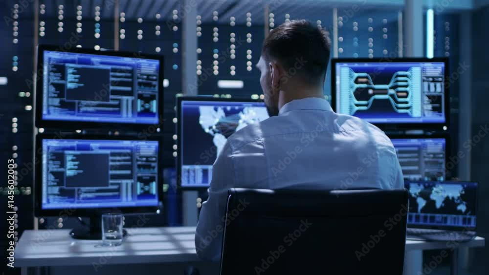 Leinwandbilder back view of technical controller/ operator working at his workstation with multiple displays. possi