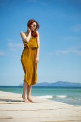 Fototapeta na wymiar red haired woman at ocean pier in sunny weather