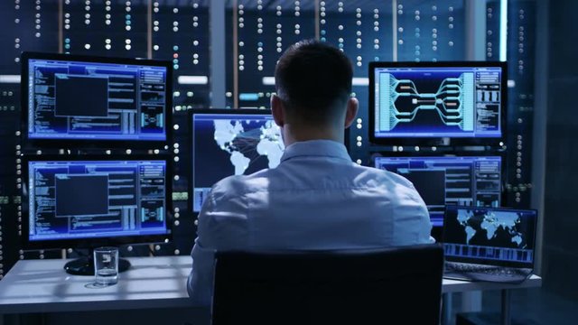 Technical Controller Working at His Workstation with Multiple Displays. Displays Show Various Technical Information. He's Alone in System Control Center. Shot on RED EPIC-W 8K Helium Cinema Camera.