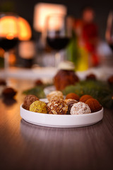 Delicious chocolates in plate on wooden table closeup