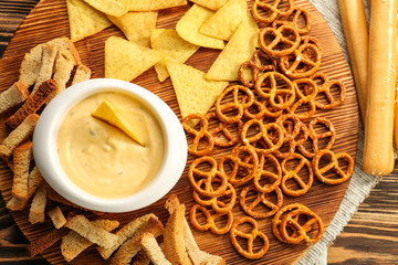 Bowl with beer cheese dip and snacks on wooden board