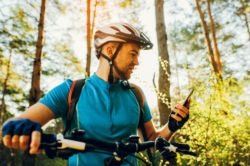 Bottom view outdoor shot of cyclist on bike using navigator on smart phone, explore map and search...