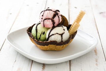 Ice cream scoops served in waffle basket on white wooden table

