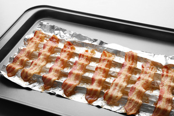 Baking tray with strips of fried bacon on table