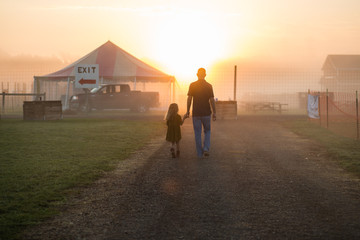 Father and daughter holding hands on road in sunlight