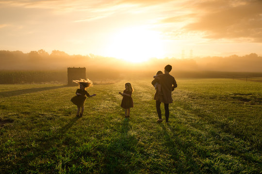 Mother and daughters playing in field during sunset