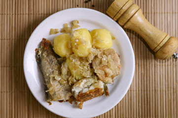 Fried fish and boiled potatoes on a plate.