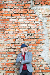 Fototapeta na wymiar Senior man with smartphone making phone call against brick wall.