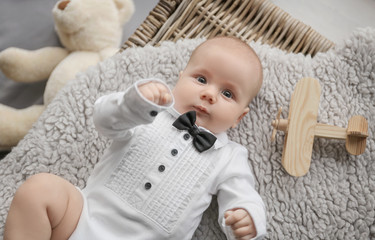 Cute little baby in stylish outfit lying on soft blanket