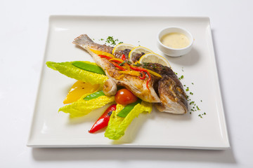 Grilled whole fish decorated with leaves of lettuce and cherry tomato, served with garlic sauce. Fried whole fish