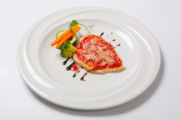 grilled Chicken breasts coated with melted cheese, vegetables and tomato sauce on a white plate
