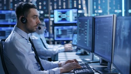  In the System Control Center Technical Support Team Gives Instructions with the Help of the Headsets. Room is Full of Displays with Various Data on them. Shot on RED EPIC-W 8K Helium Cinema Camera. - Powered by Adobe