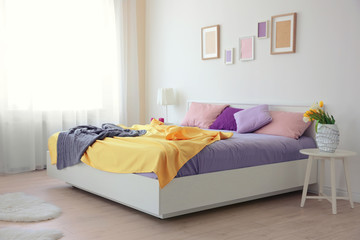 Fototapeta na wymiar Interior of light bedroom with lilac bedding