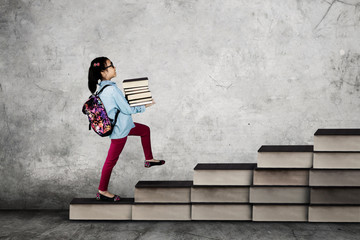 Little school girl carrying books