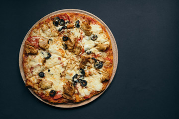 Homemade pizza with tomatoes, mozzarella and basil. Top view with copy space on dark stone table