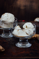 White ginger ice cream on transparent glass on black surface.