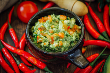 Guacamole dip with ingredietns in black ceramic bowl.