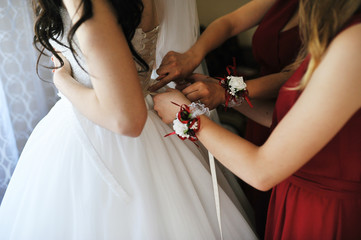 Happy cheerful brunette bride wearing at her room with two bridesmaids on red dress.