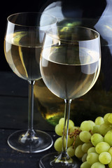 Bottle and glass of white wine, grape on wooden table
