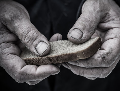 Dirty hands of a man clamped a piece of bread.
