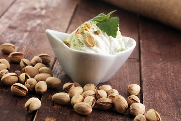 Pistachio ice cream with chopped nuts and honey on a rustic background