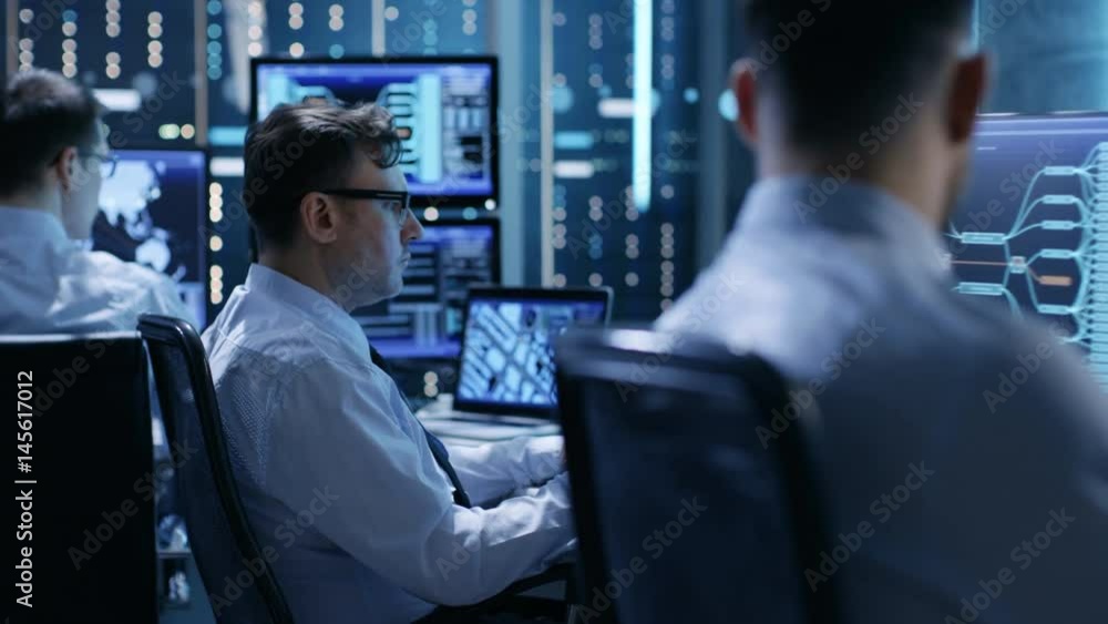 Aufkleber in the monitoring room team of system engineers working at their workstations. multiple displays sho