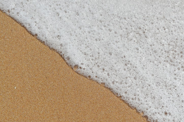 Fototapeta na wymiar Foam from the beach waves in Algarve, Portugal