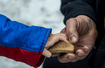 The child gives the man a piece of rye bread.
