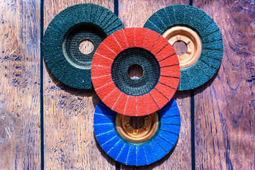 Grinder discs. A pile of color flap abrasive industrial disks on wood background texture. Great for grinding, metal finishing, sanding steel or inox. Grinder discs - professional equipment