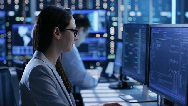 Close-up Footage of Female IT Engineer Working in Monitoring Room. She Works with Multiple Displays. Shot on RED EPIC-W 8K Helium Cinema Camera.
