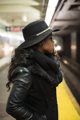 A young, black woman waits at a NYC subway platform. Shot during The Spring of 2017