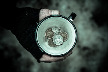 Dirty hand of a person grips a metal Cup In a mug find the coins.
