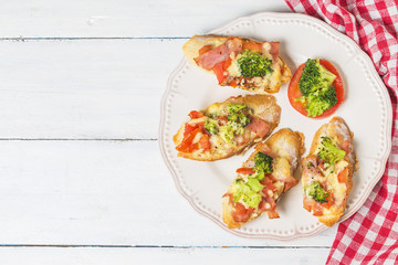 open sandwich with prosciutto, mozzarella and tomatoes on kitchen table, shallow focus