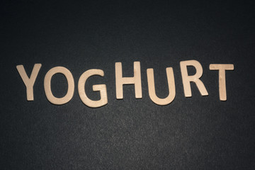 Yoghurt written with colorful wooden letters on a black background