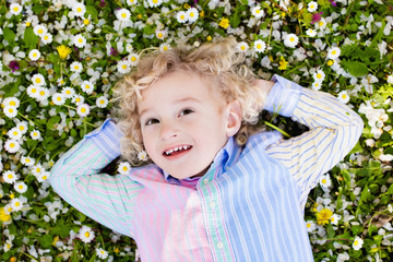 Child on green grass lawn with summer flowers