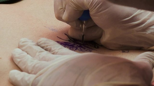 Tattoo artist paints a butterfly on a man's belly