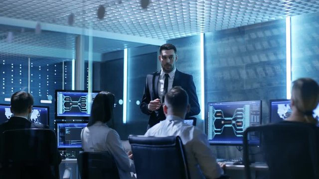 Supervisor Holds Briefing for His Employees in System Control Center Full of Monitors and Servers. Possibly Government Agency Conducts Investigation. Shot on RED EPIC-W 8K Helium Cinema Camera.
