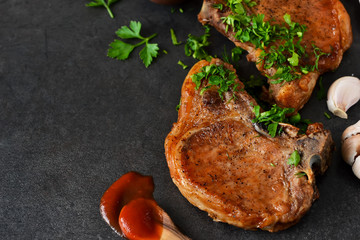 Juicy grilled pork steak with pesto sauce and tomato sauce on a black background