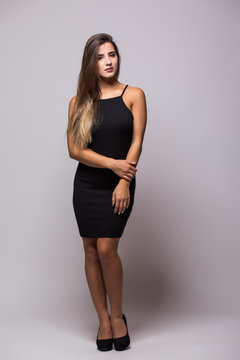 Full length portrait of a sexy woman in little black fashion dress on grey