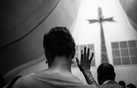 A black woman crosses her fingers in the church. 