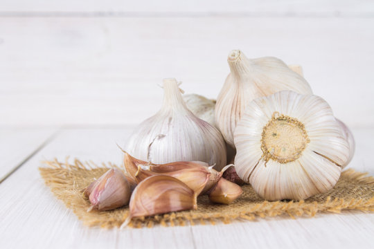Garlic cloves and garlic bulb on a white wooden table.