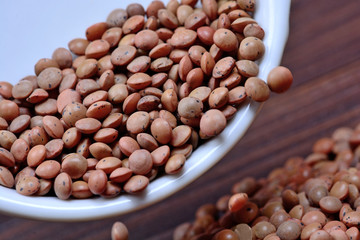 Brown lentils spilling from a bowl on table