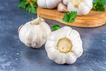 Garlic cloves and garlic bulb on a wooden board on a gray background.