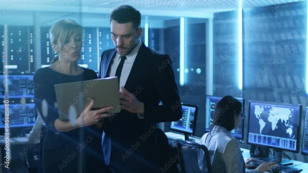 Poster in system control room female and male top managers have discussion. in the background professional 
