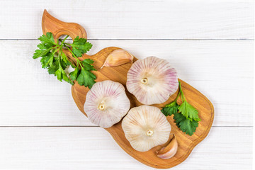 Garlic cloves and garlic bulb on a wooden board on a white background. Top view