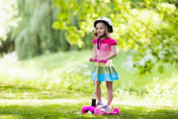 Little girl riding a colorful scooter