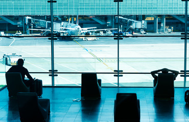 Obraz premium Silhouettes of people waiting for their flight at the airport.