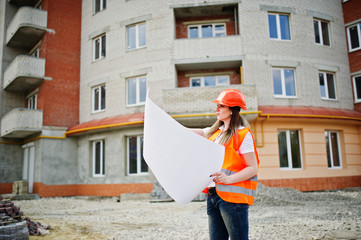 Engineer builder woman in uniform waistcoat and orange protective helmet hold business paper...