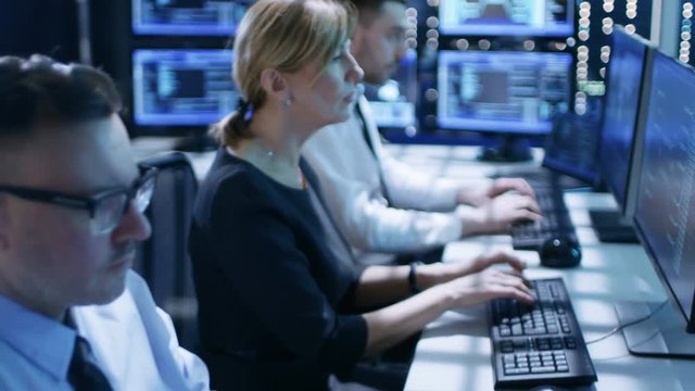 Dolly Shot of Engineers Working on Their Computers in Monitoring Room. Many Screens with Various Data and Information are in the Room.Shot on RED EPIC-W 8K Helium Cinema Camera.